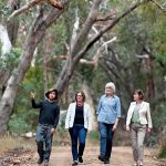 four people walking on roadside